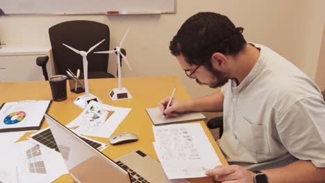man working on renewable energy project with wind turbine models