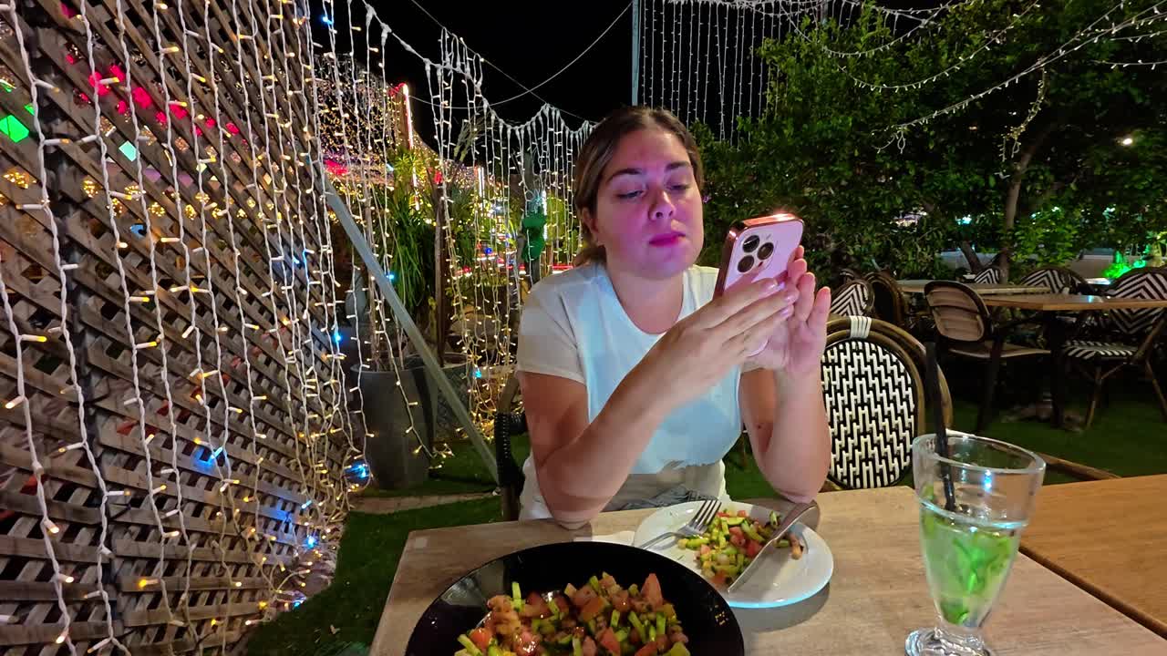 Woman Texting on Her Phone While Dining Outdoors at Night