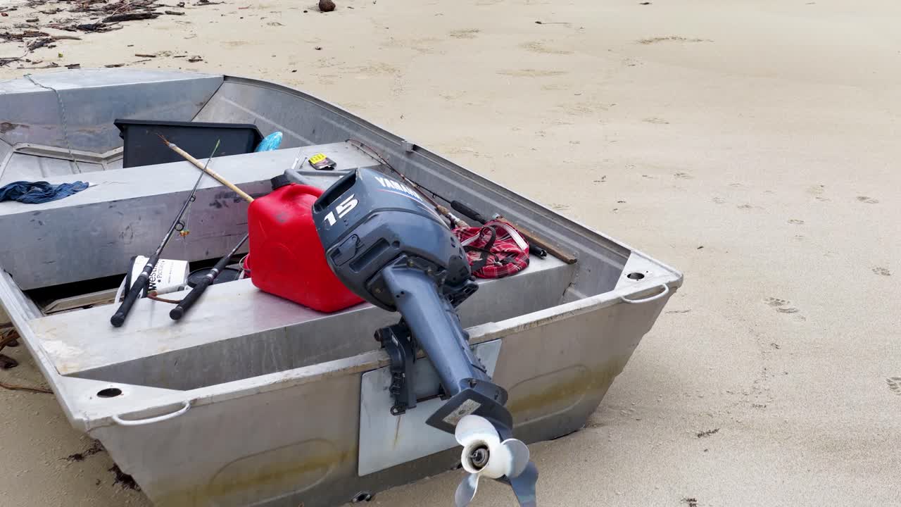 Aerial view of a small, empty boat on a sandy beach, captured by a drone in natural lighting