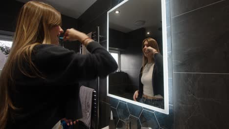 female model looking in a bathroom backlit mirror washing her teeth