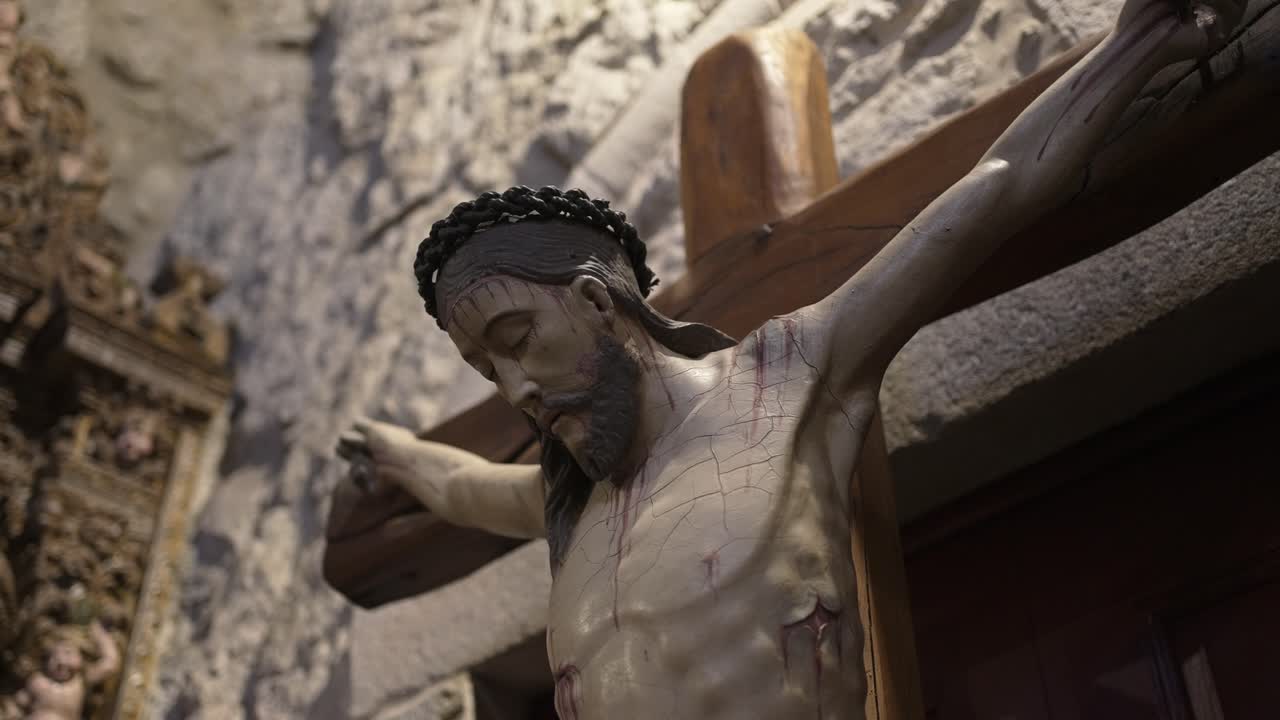 Wooden statue of Jesus Christ on the cross, depicting detailed craftsmanship, emotion, and devotion