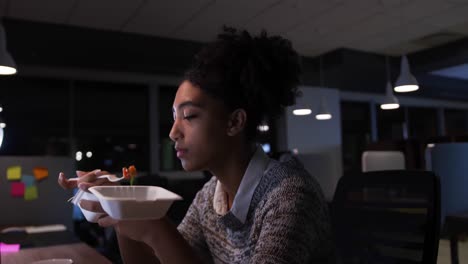 businesswoman working and eating in a modern office by night