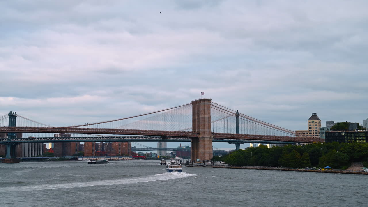 Ampia vista dello skyline del Ponte di Brooklyn e del Ponte di Manhattan dal fiume. Paesaggio panoramico dell'East River con i ponti di Brooklyn e Manhattan sotto un cielo coperto.