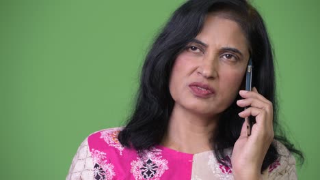 mujer india hermosa madura pensando mientras habla por teléfono