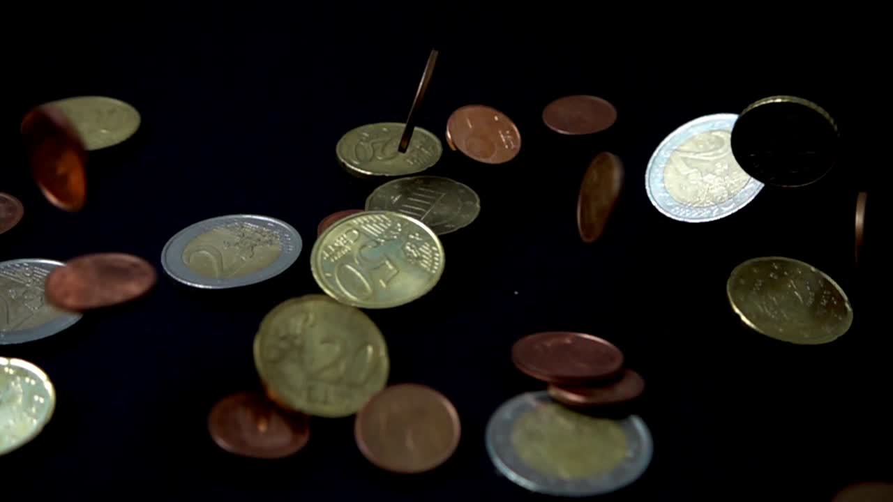 Coins fall on a black background. Slow motion