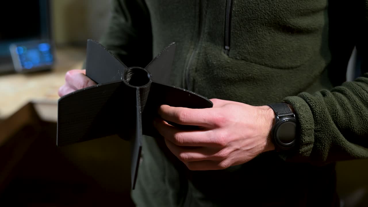 A soldier from a drone brigade holds a 3D-printed rocket wing for drone attachment. This innovative, inexpensive tech enables expendable drones to reshape warfare in the Ukraine-Russia conflict
