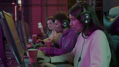 concentrated female gamer playing video games and eating potato chips in a gaming club