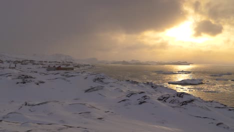 Breiter-Zeitlupenschwenk-Der-Küstenstadt-Lulissat-In-Grönland-Bei-Sonnenuntergang-Mit-Eisbergen-Und-Gletschern-Im-Hintergrund