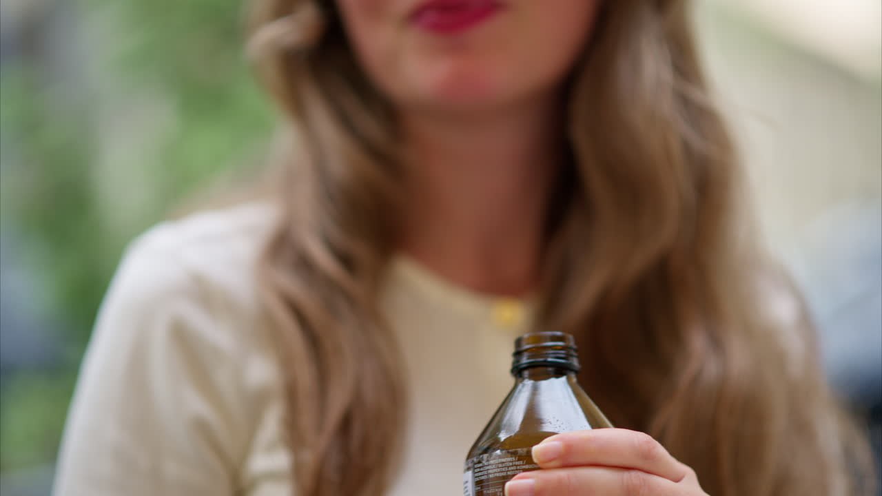 Close-up of brunette, young woman drinking a kombucha tea outside