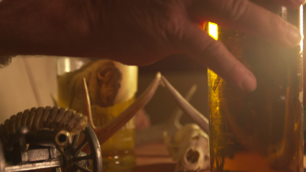 el hombre agarra el whisky de la mesa con cuernos de ciervo y un pequeño cañón