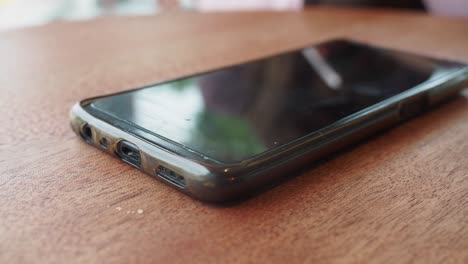 a black smartphone with a case on a wooden table