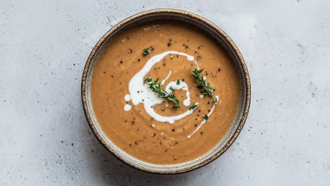 sopa de verduras cremosa con un remolino de tomillo y crema