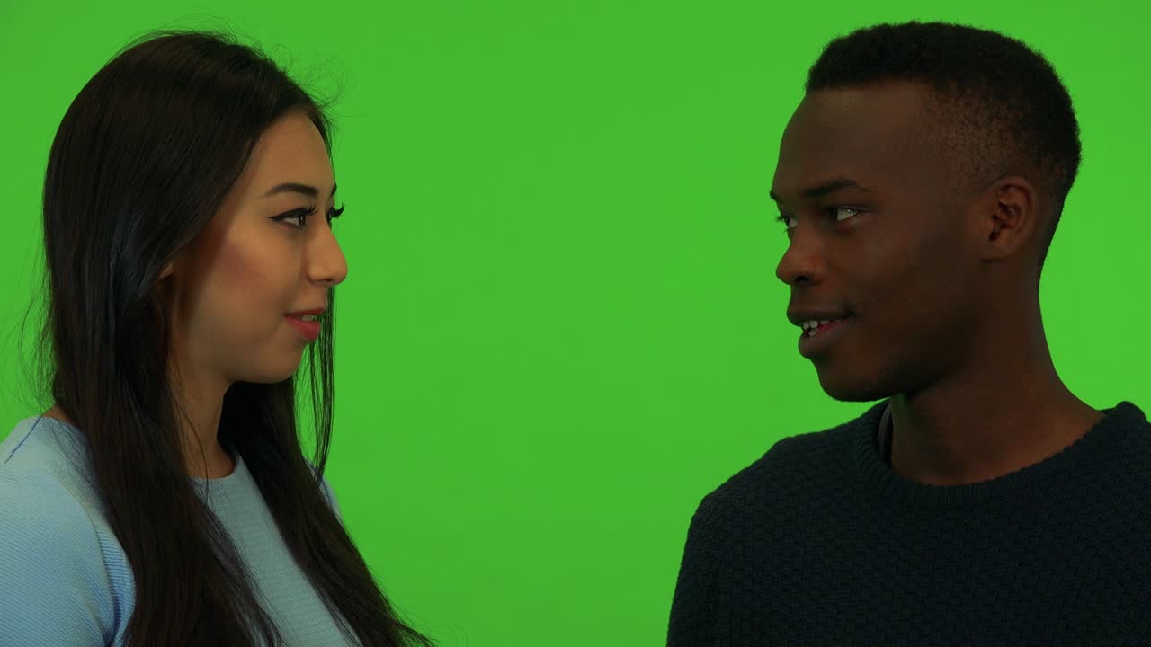 una joven asiática y un joven negro hablan - primer plano en las caras - estudio de pantalla verde