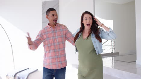 smiling pregnant woman and partner exploring new home together, feeling excited