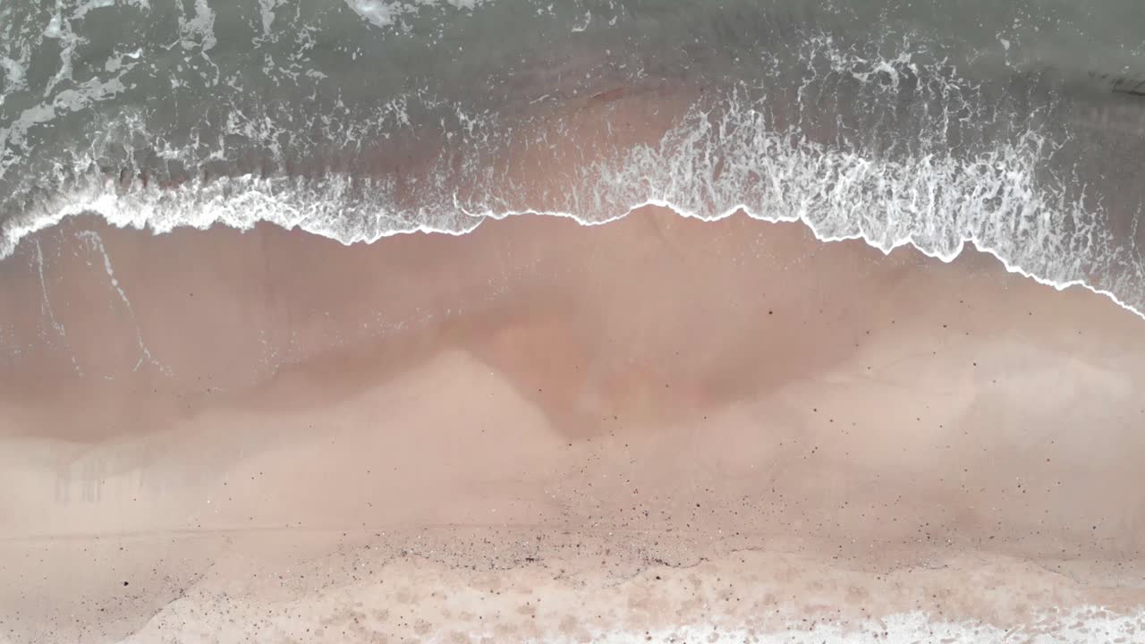 Luftfoto af bølger, der slår ind på sandstranden ved Ustka om vinteren.