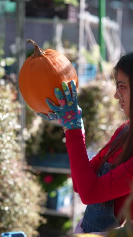 mujer joven sosteniendo una calabaza en un jardín