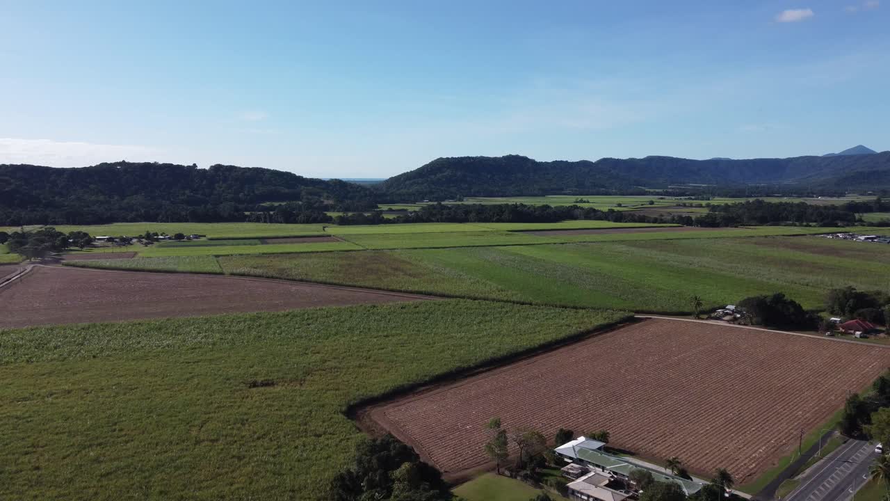 Drone flying over part of a small rural town towards a large sugarcane plantation in North Queensland, Australia