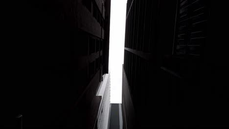 Looking-Up-In-An-Alleyway-Between-Buildings-In-Sydney,-NSW,-Australia---low-angle-shot