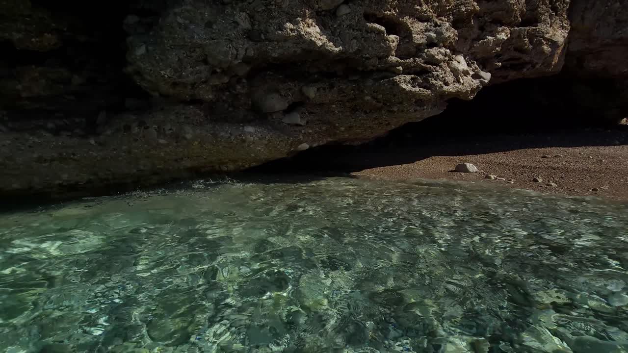 el agua cristalina del mar salpicando bajo los acantilados, reflejando la luz del sol en el fondo del mar con piedras blancas, hermosa bahía en el mediterráneo