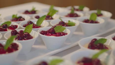 Close-up-of-many-cups-of-cherry-compole-with-peppermint-leaves-presented-in-white-china-cups-at-a-buffet