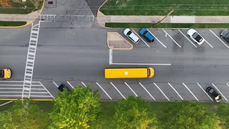 yellow school buses driving towards school entrance in america