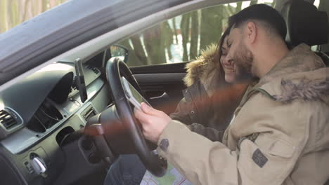 caucasian couple taking pictures of each other inside a car.