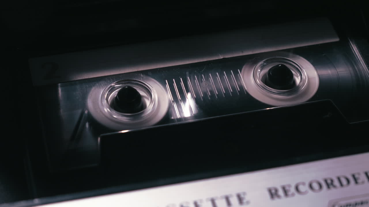 Primo piano di una cassetta a nastro analogica che gira in un'atmosfera di scarsa illuminazione. Scena mediatica suggestiva, ideale per storie di crimine, interviste, archivi o indagini.