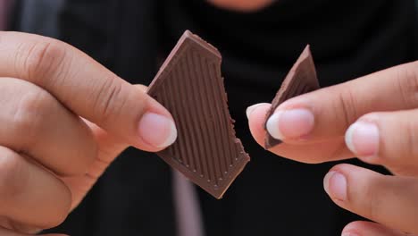 woman holding a piece of dark chocolate