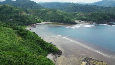 cinematic aerial dolly shot of tropical lagoon with lush mountains and picturesque ocean coastline with crashing waves