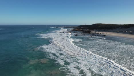 drone sobrevuela la espuma del mar hacia el faro de corny point