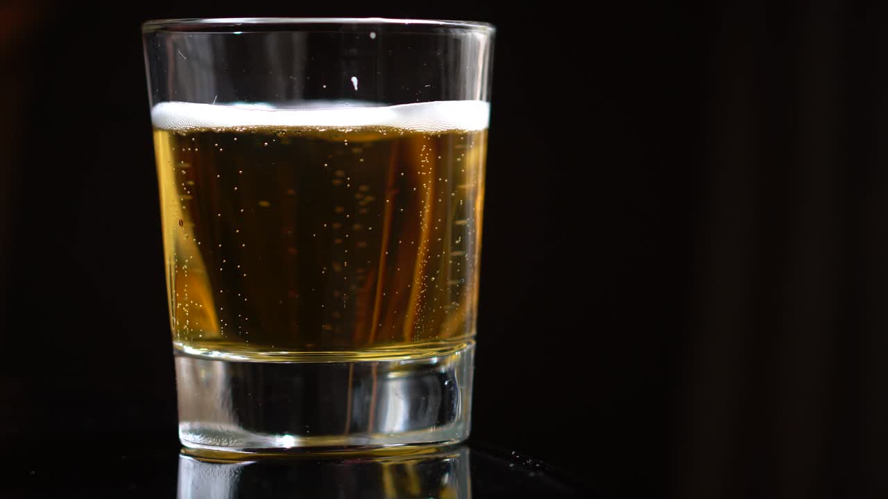 video 4k de cerveza fría en un vaso con gotas de agua