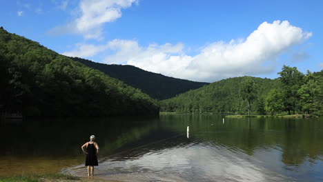 a woman looks out upon sherando lake, part of the george washington national forest, in virginia's blue ridge mountains