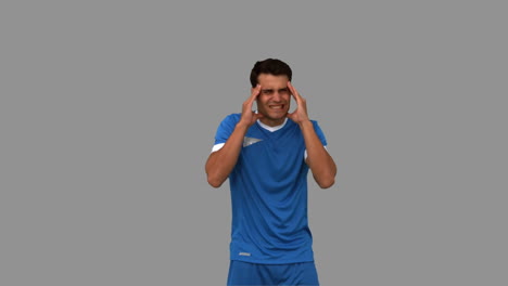 jugador de fútbol sufriendo de dolor de cabeza en la pantalla gris