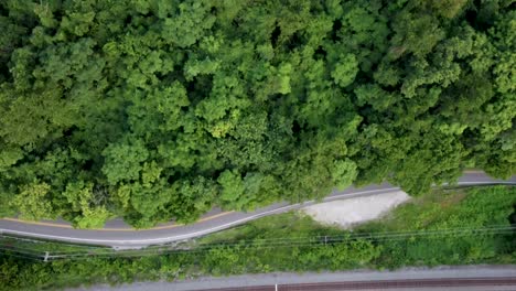 Drohnenaufnahmen-Einer-Straße-In-Einem-Wald-Mit-Einem-Auto,-Das-Die-Straße-Entlangfährt