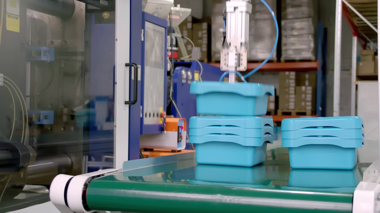 Automated robotic arms stacking blue plastic bins on the conveyor belt
