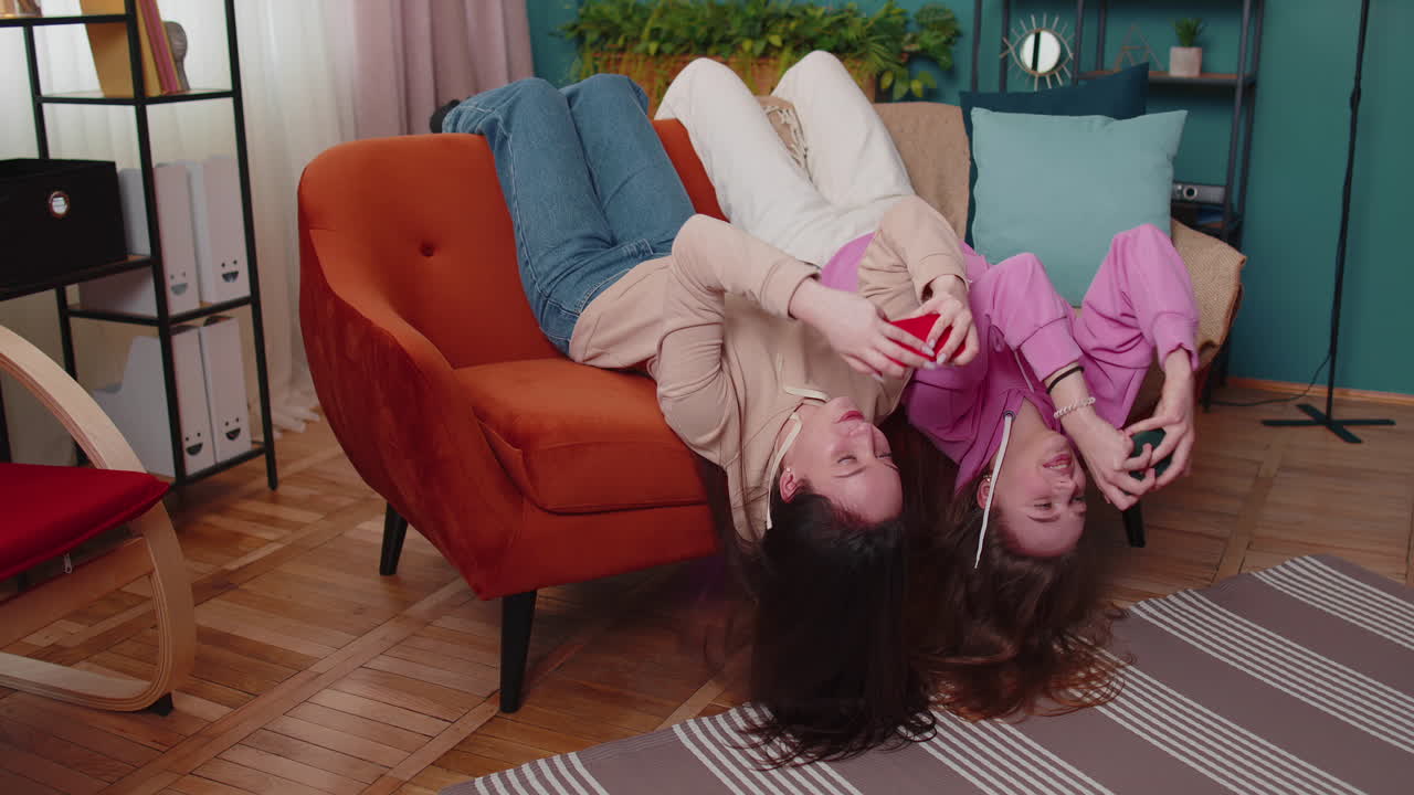 беспокойные две смешные девушки друзья братья и сестры с энтузиазмом играют в гоночные видеоигры на смартфоне