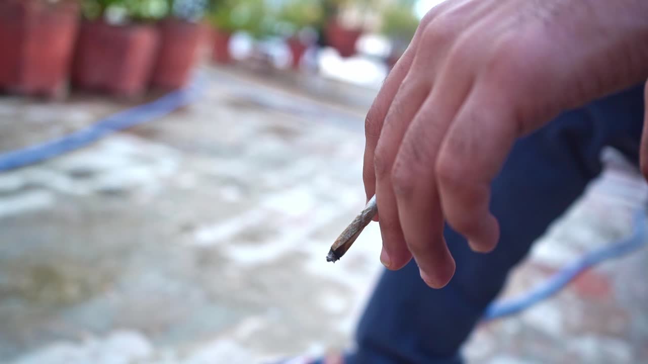 hombre indio fumando mientras la mano temblaba con su cigarrillo en agra india - cerrar