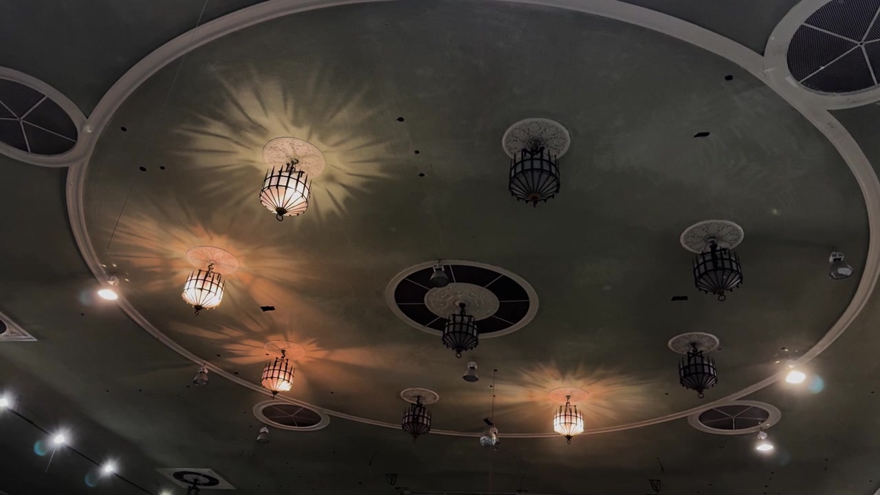 Ornate vintage ceiling lights glow in large indoor convention hall interior space