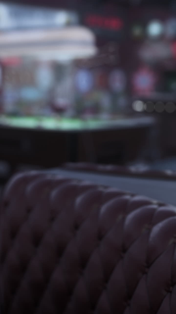 뒷면에 풀 테이블이 있는 어두운 바에 있는 빈티지 티드 브라운 가죽 소파