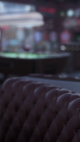 vintage tufted brown leather couch in a dark bar with a pool table in the background