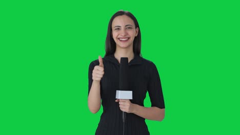 Happy-Indian-female-news-reporter-showing-thumbs-up-Green-screen
