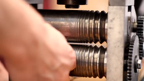 jeweler craftsman processes silver chain with forge rolling machine at workplace in jewelry workshop.