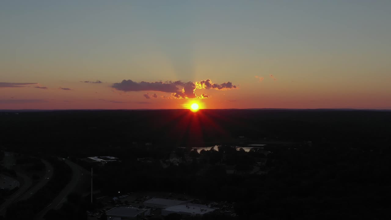aerial trucking shot over a rural area in the Northeast with epic centered sunset with amazing colors