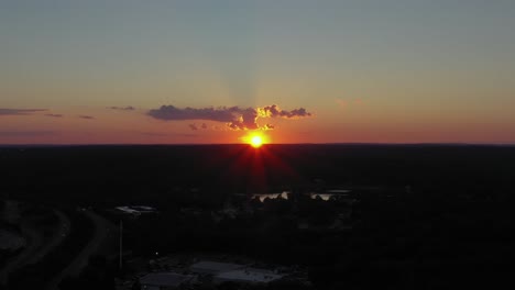 aerial trucking shot over a rural area in the northeast with epic centered sunset with amazing colors