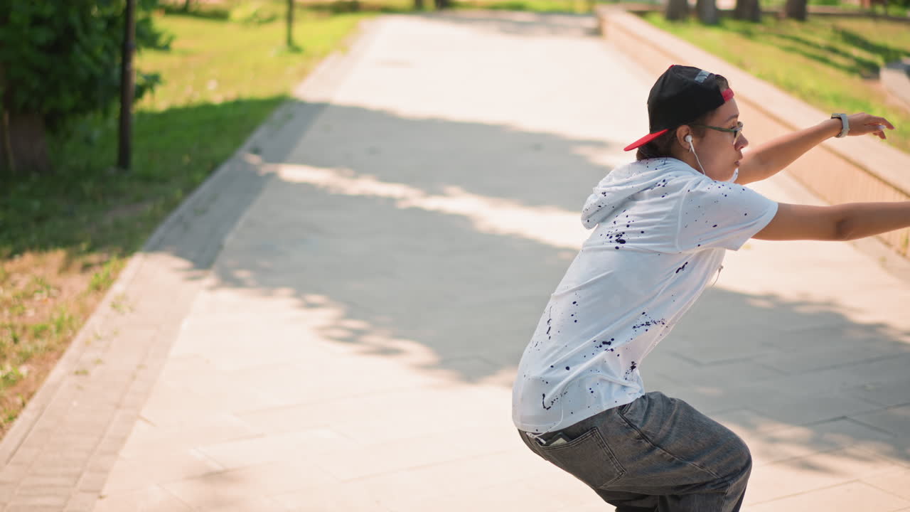 Casual dancer on sunny path, Individual with headphones dancing along brightly lit riverside trail, Person in laidback attire engaging in lively dance routines besidesunny river walkway