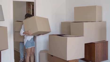 joven novio y novia entrando en la habitación y cargando cajas de cartón