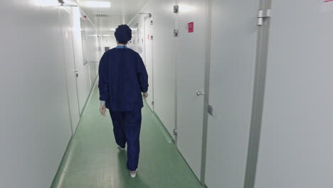병원 복도 에서 걸어다니는 보호 유니폼 을 입은 여성 의사 의 뒷면