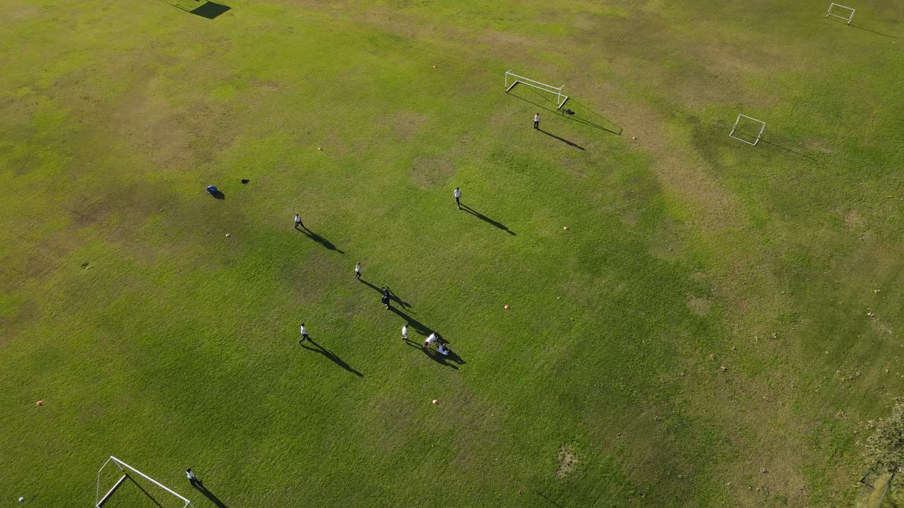 여름 동안 녹색 잔디밭에서 축구를 하는 어린이 팀을 보여주는 공중 드론 샷