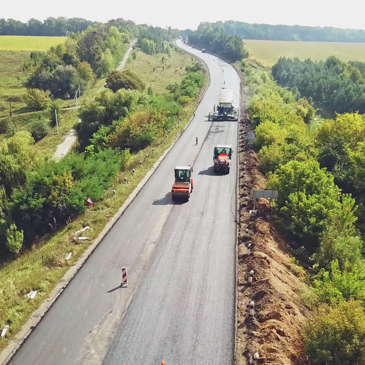 Aerial view. Laying a new asphalt on the road. Road repair machine with heavy vibration roller compactor