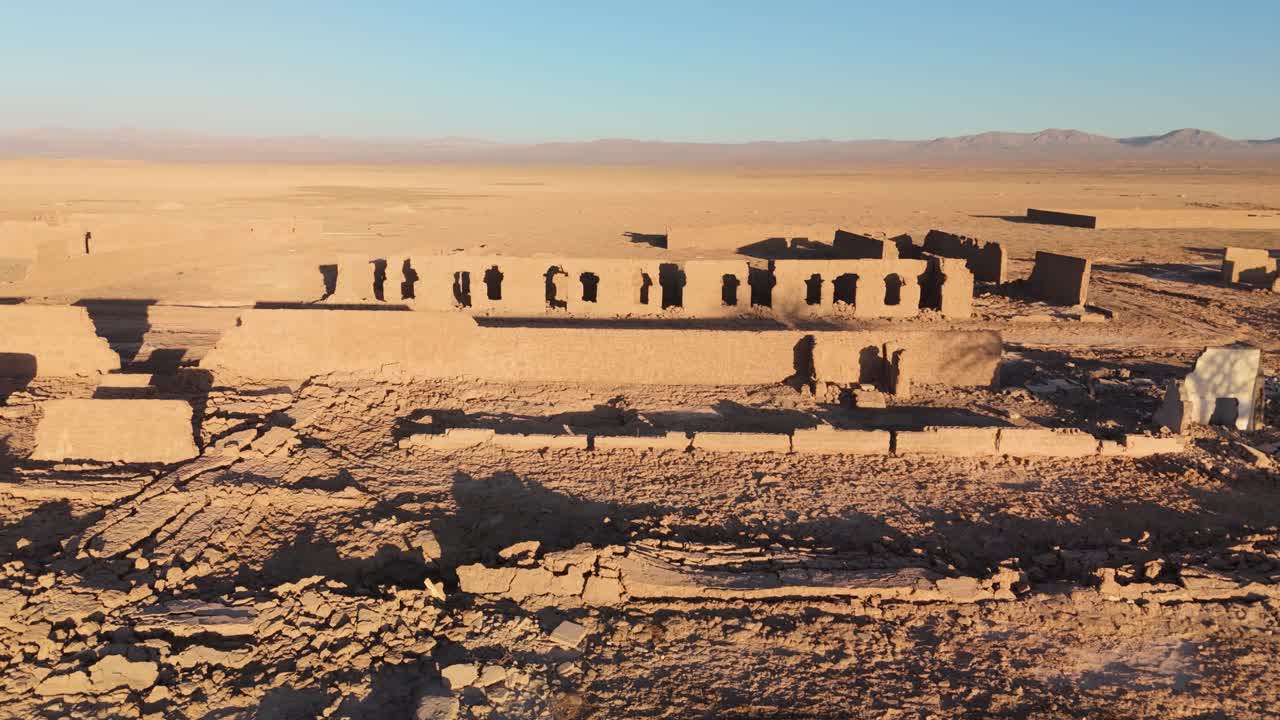 Drone image of abandoned ruined adobe facades, image descending to pass over the walls